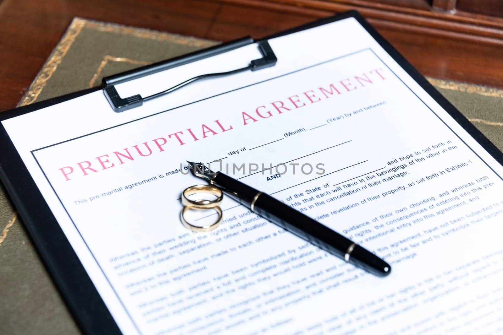 Close-up of a prenuptial agreement form with wedding rings and a fountain pen, indicating the legal aspects of marriage preparation. by jbruiz78