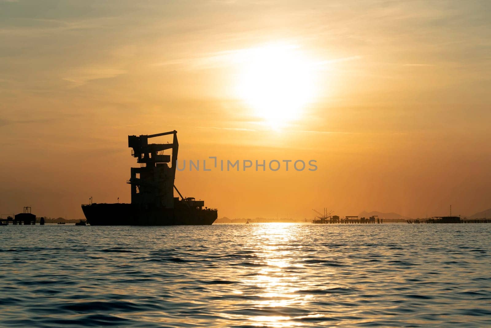 grain silos descharghing ship at Sunset in Venice lagoon chioggia harbor by AndreaIzzotti
