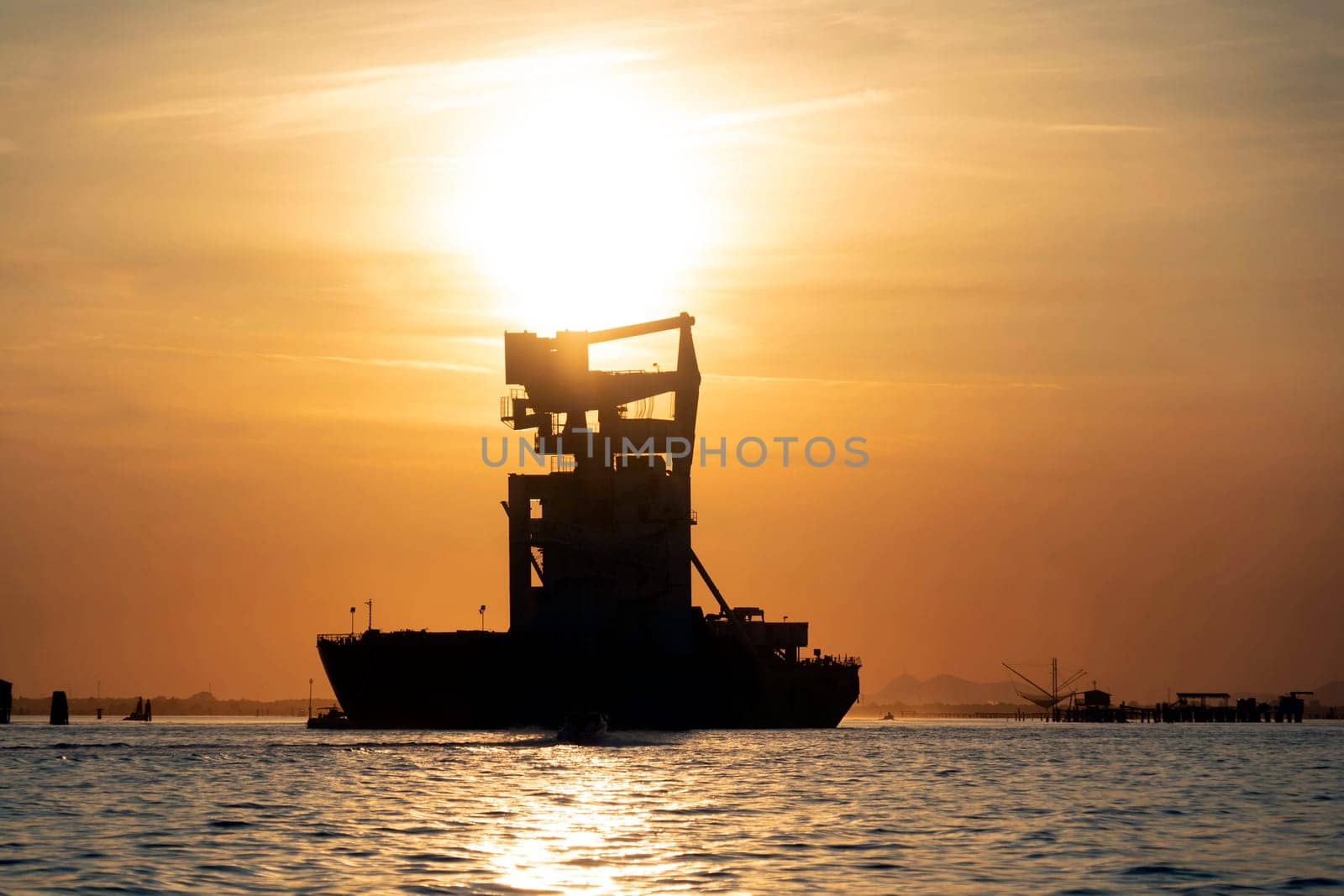 grain silos descharghing ship silhouette at Sunset in Venice lagoon chioggia harbor