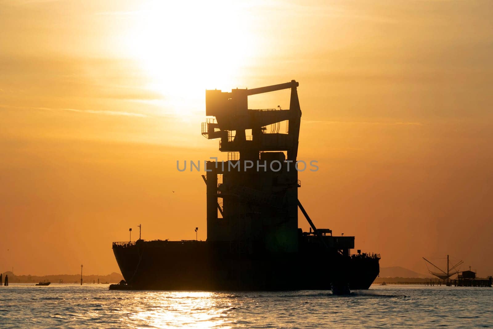 grain silos descharghing ship silhouette at Sunset in Venice lagoon chioggia harbor