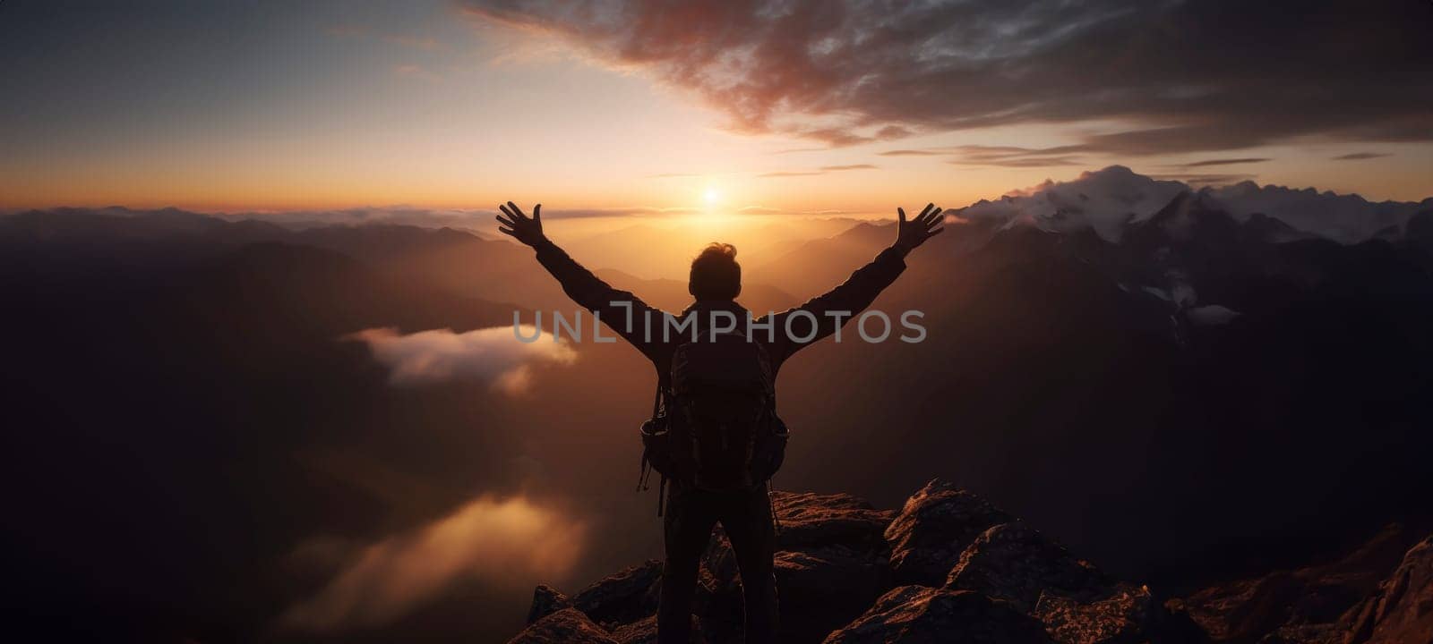 Explorer with raised arms facing sunrise over mountains. Adventure and exploration concept with copy space for design and print