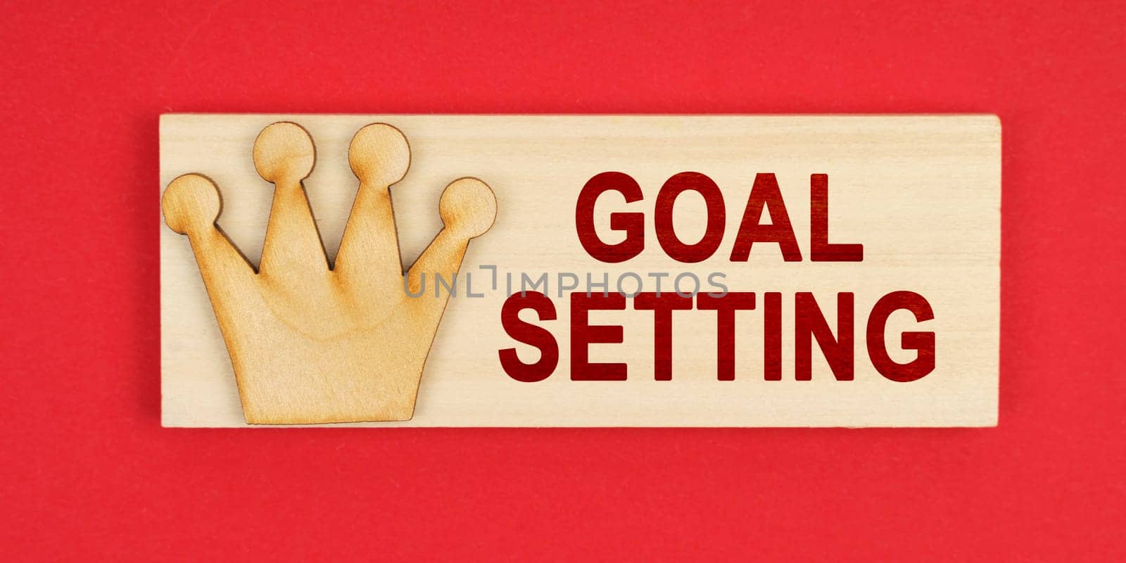 Leader concept. On a red surface there is a wooden block with the inscription - Goal setting