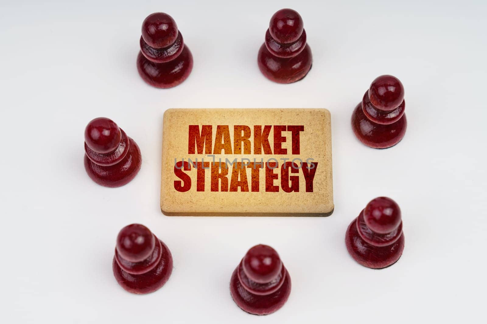 Business concept. On a white background, pawns stand around a sign with the inscription - Market Strategy