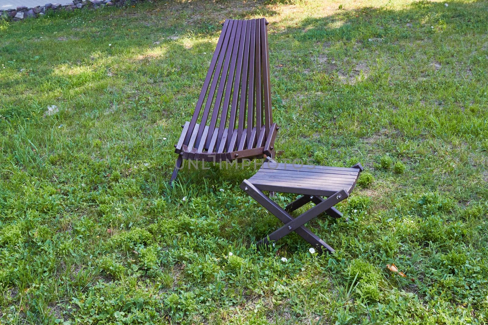 Photo wooden folding table and armchair. Outdoor furniture for recreation. Against a background of green grass.