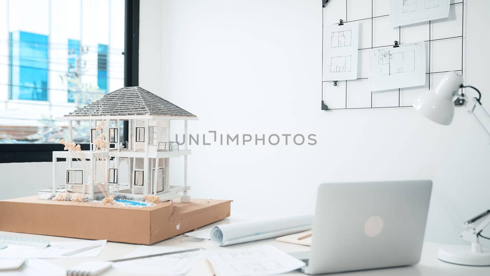Closeup image of modern house model, laptop, blueprint and architectural equipment placed on table at modern meeting room. Creative business living and design concept. Architect table. Immaculate.