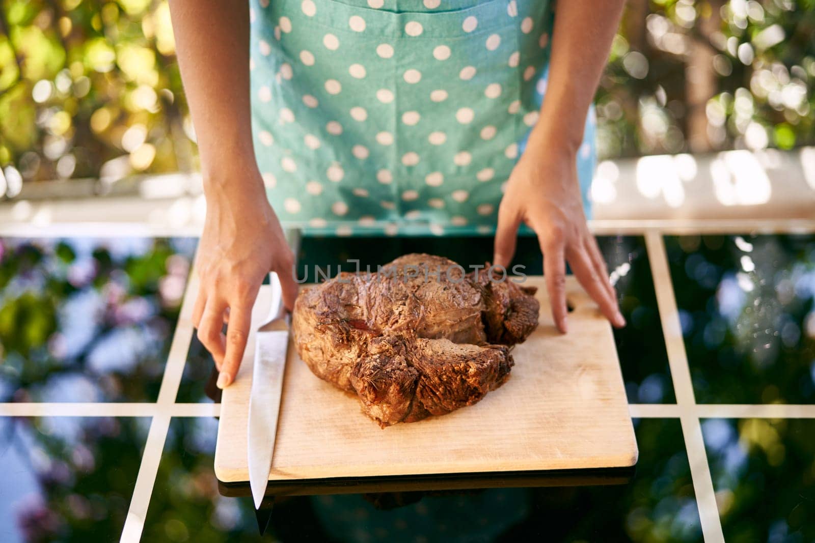 Housewife touches with her fingertips a cutting board with roast beef on the table. High quality photo