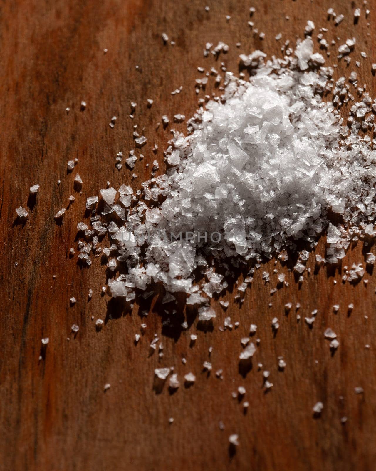 Close-up of coarse sea salt crystals on a wooden background, highlighting texture