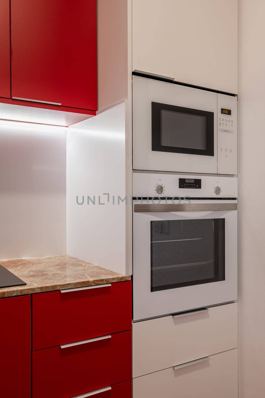 Close-up view of a modern kitchen's integrated appliances, including a microwave and oven set into white cabinetry.