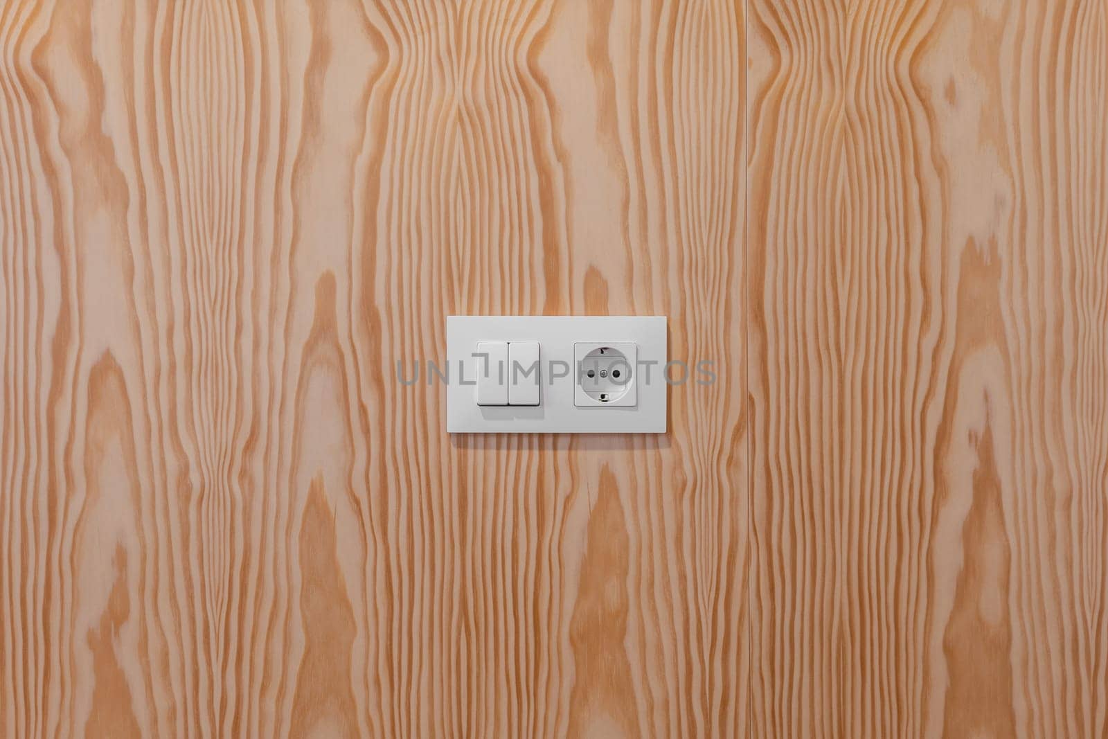 Minimalistic light switch and power outlet on a textured wooden wall by apavlin
