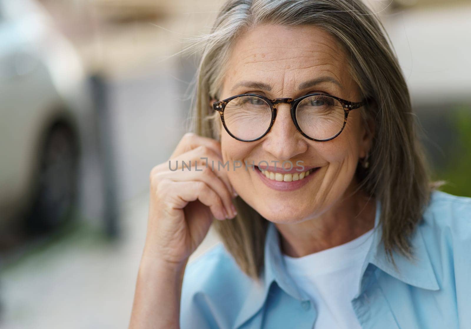 An elderly woman wearing glasses and a blue shirt.