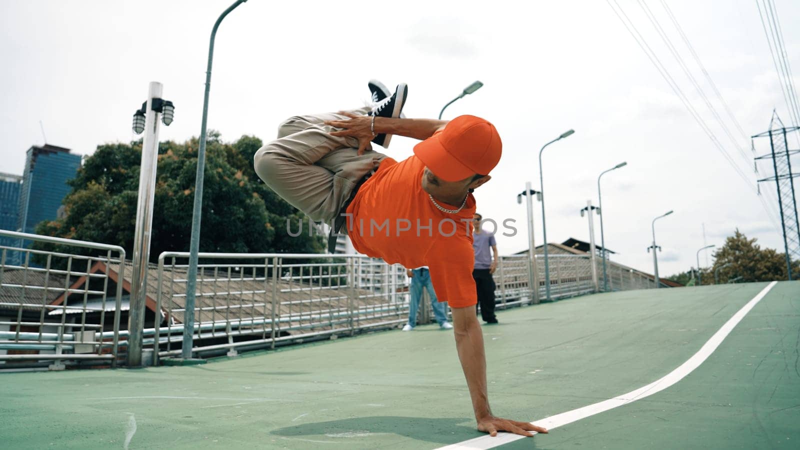 Young happy hipster perform break dancing or foot step with friend moving to hiphop music together. Skilled dancer doing freeze pose and waving hand. Modern lifestyle. Outdoor music 2024. Sprightly.