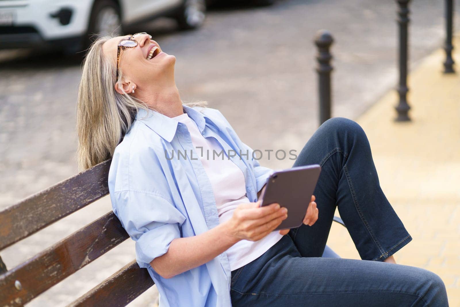 A woman sitting on a bench, gazing upwards at an object or view in front of her.