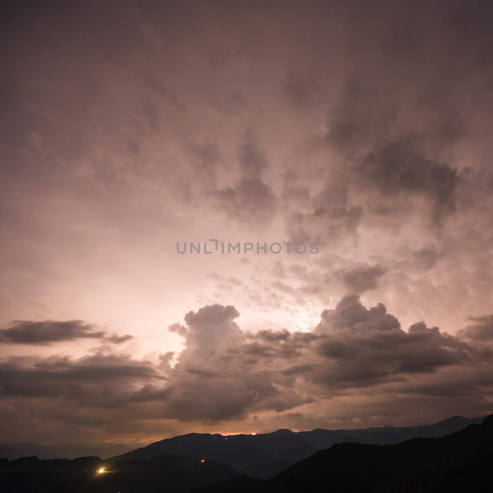 Evening thunderstorm with lightning in the mountains. Dramatic clouds during a thunderstorm pierce the light of lightning in a mountainous area. by Niko_Cingaryuk
