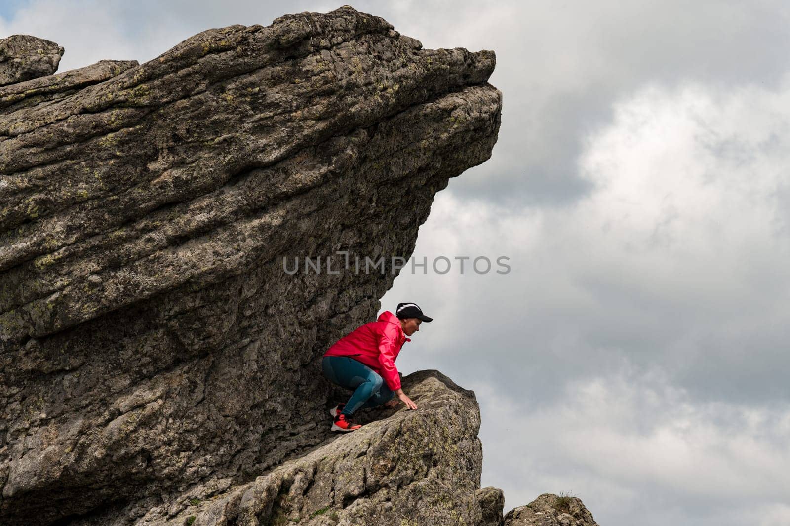 A woman climber climbed high on a dangerous rock.