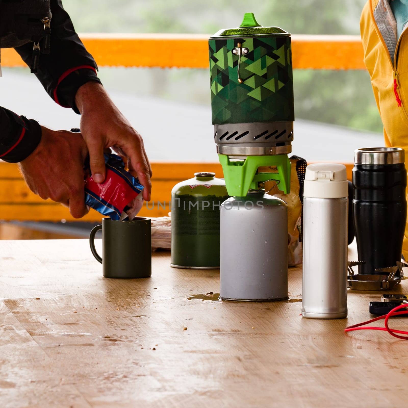 Tourists make coffee using gas cylinders in a tourist shelter on a wooden table.