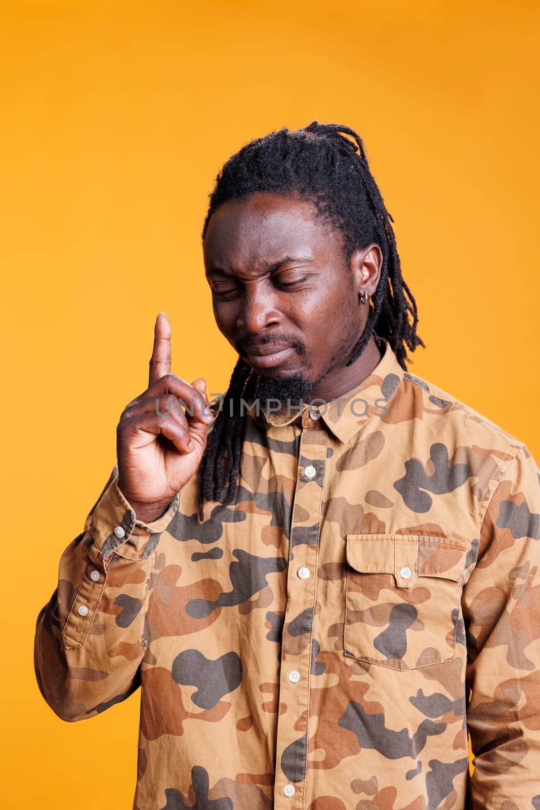 Concentrated man brainstorming ideas to find solution, taking thoughts into consideration while posing over yellow background in studio. Uncertain young adult contemplating about serious problem.