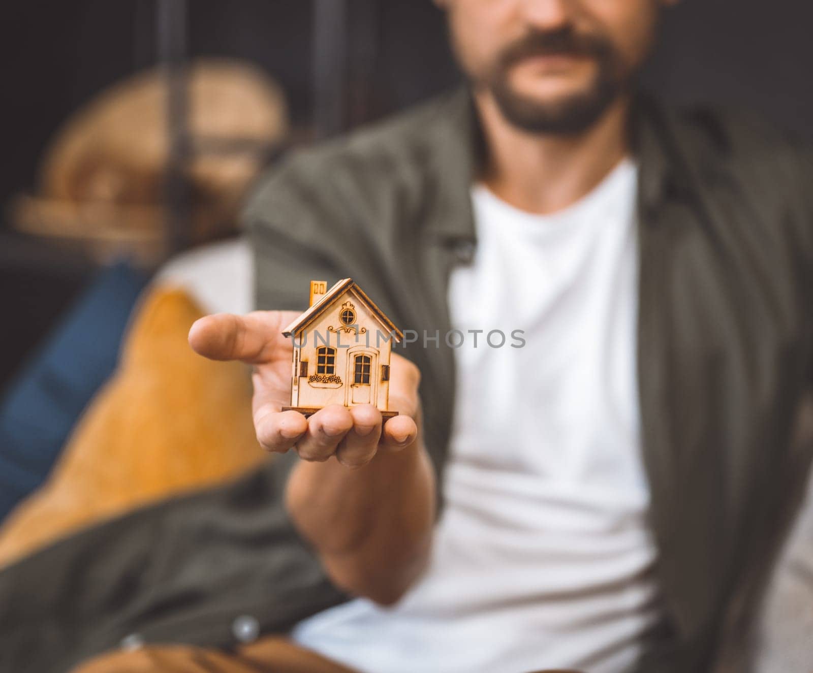 Man holding a small wooden house in his hand.