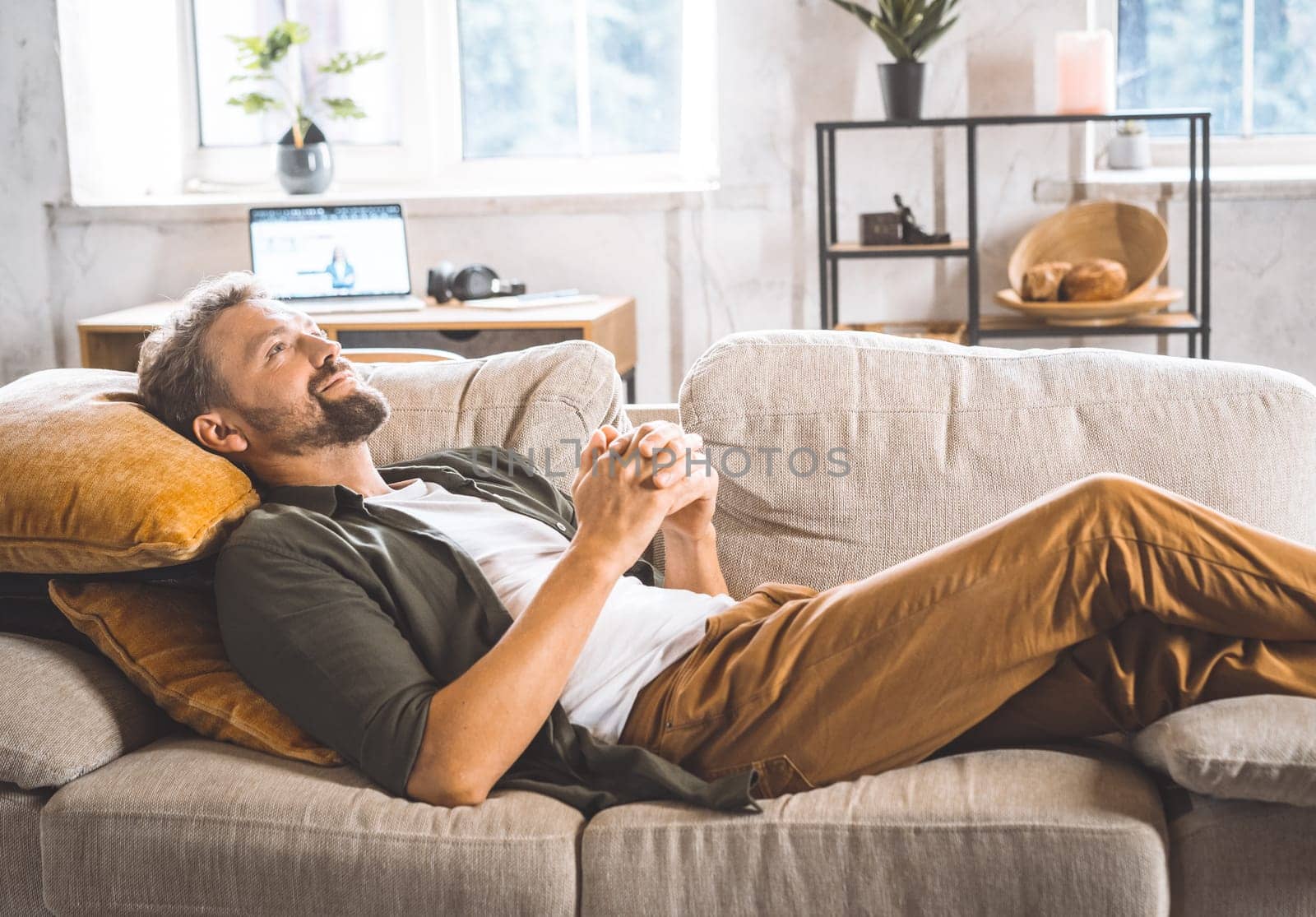 A man laying down on a couch with a pillow placed on his back.