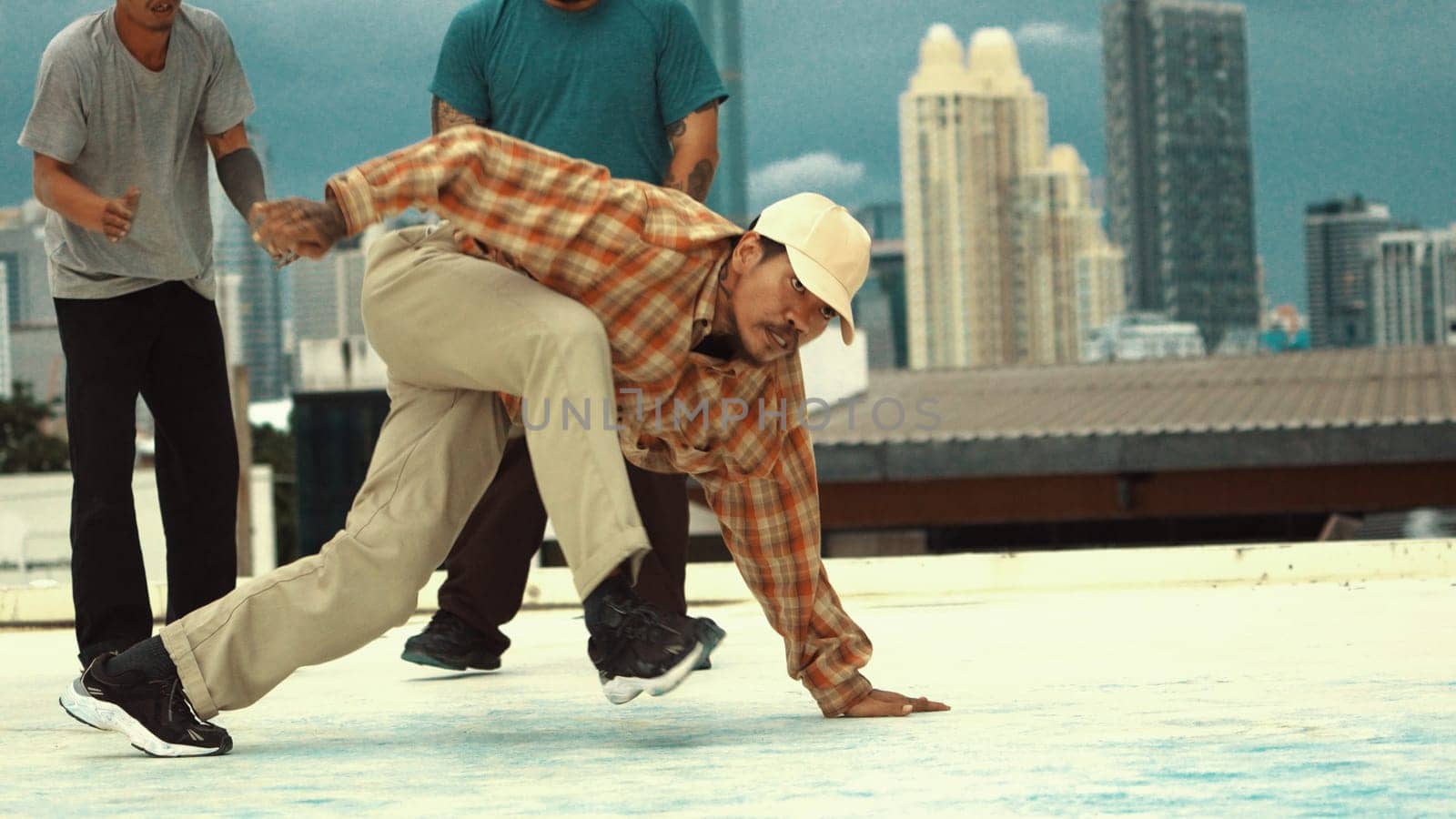 Motion shot of skilled hipster doing break dance at sky scrapper. Professional break dancer or choreographer practicing street dance at rooftop. Outdoor sport 2024. Active, energetic dance. Endeavor.