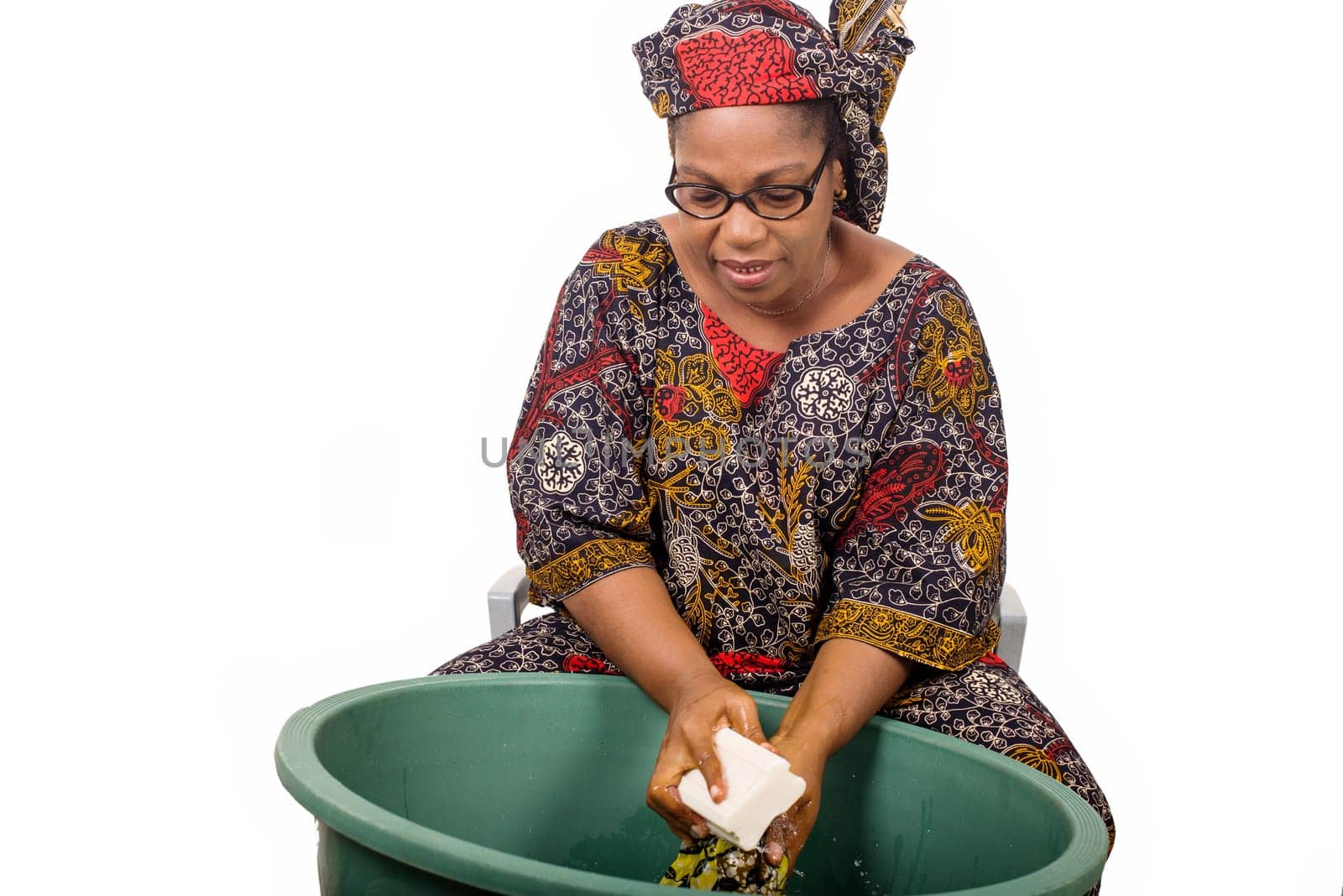 mature african woman in loincloth sitting doing laundry.