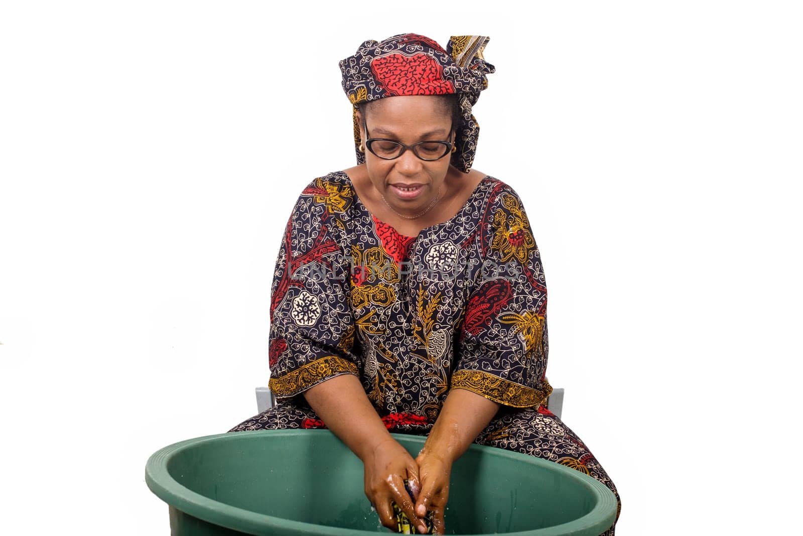 mature african woman in loincloth sitting doing laundry.