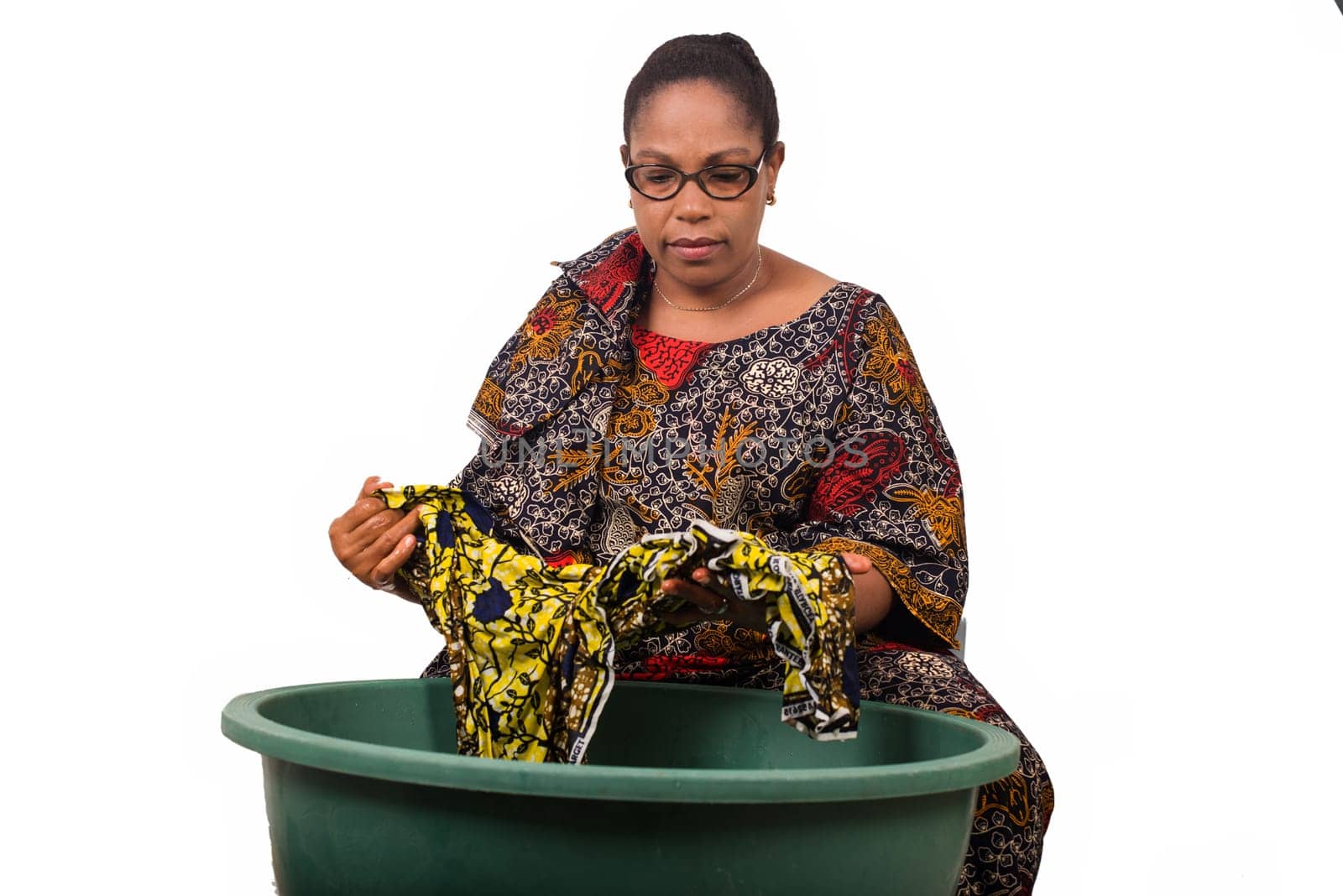 mature african woman in loincloth sitting doing laundry.