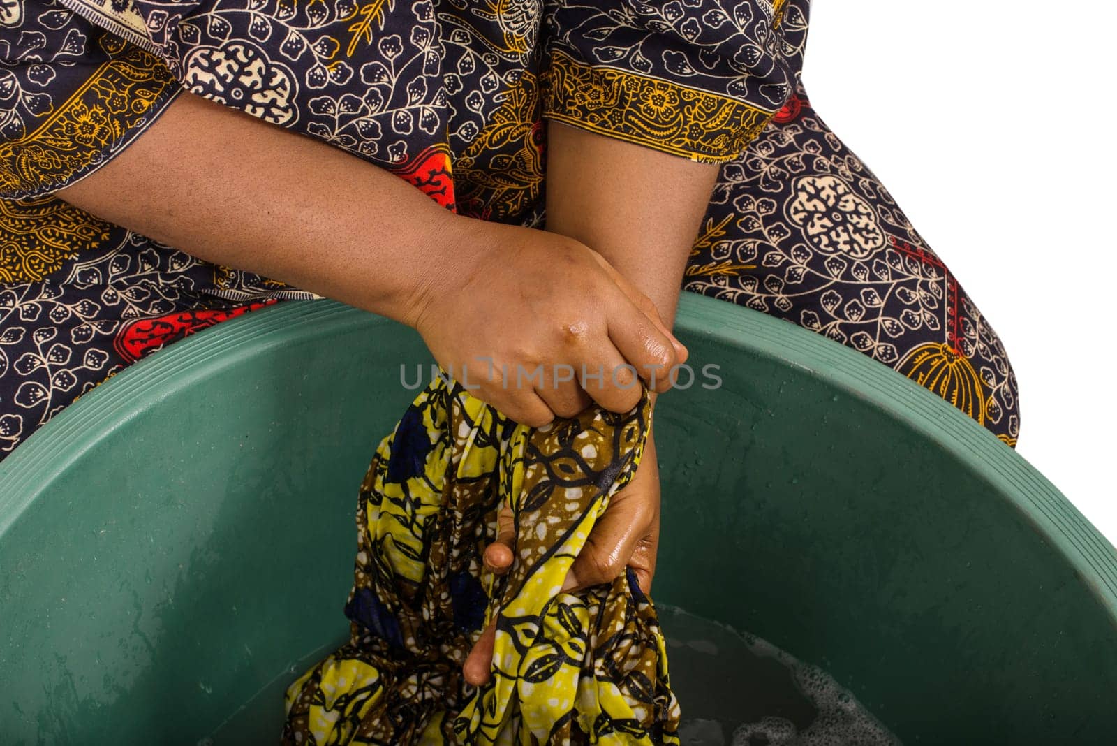 close-up of woman's hands holding an African fabric that she is washing in a big green bowl