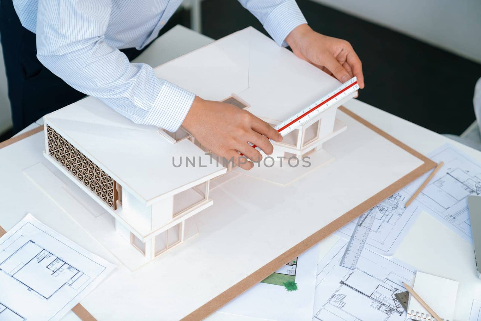 Professional engineer measures house model while skilled designer writes down in blueprint. Work together, collaboration, cooperate. Creative design and team working concept. Top view. Immaculate.