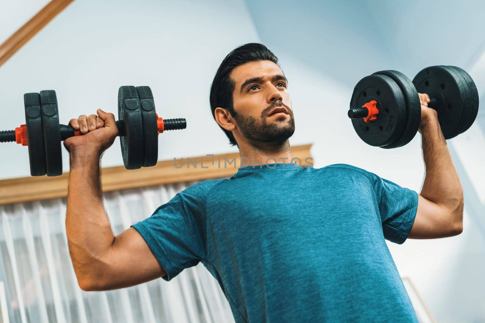 Athletic body and active sporty man lifting dumbbell weight for effective targeting muscle gain at gaiety home as concept of healthy fit body home workout lifestyle.