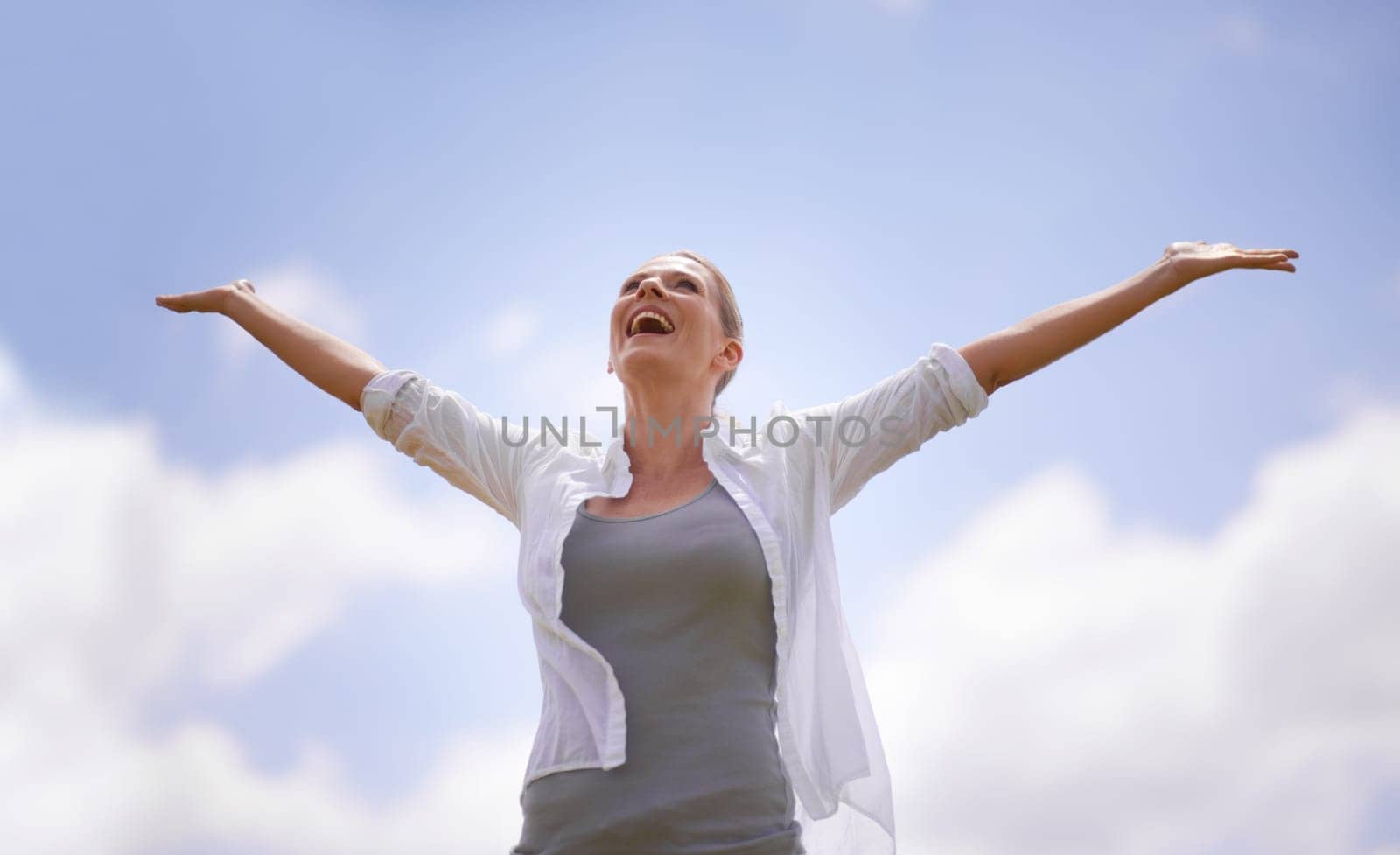 Happy woman, freedom and joy with open arms for success, health and wellness with blue sky background. Female person with smile in relax for achievement, accomplishment or winning on mockup space by YuriArcurs