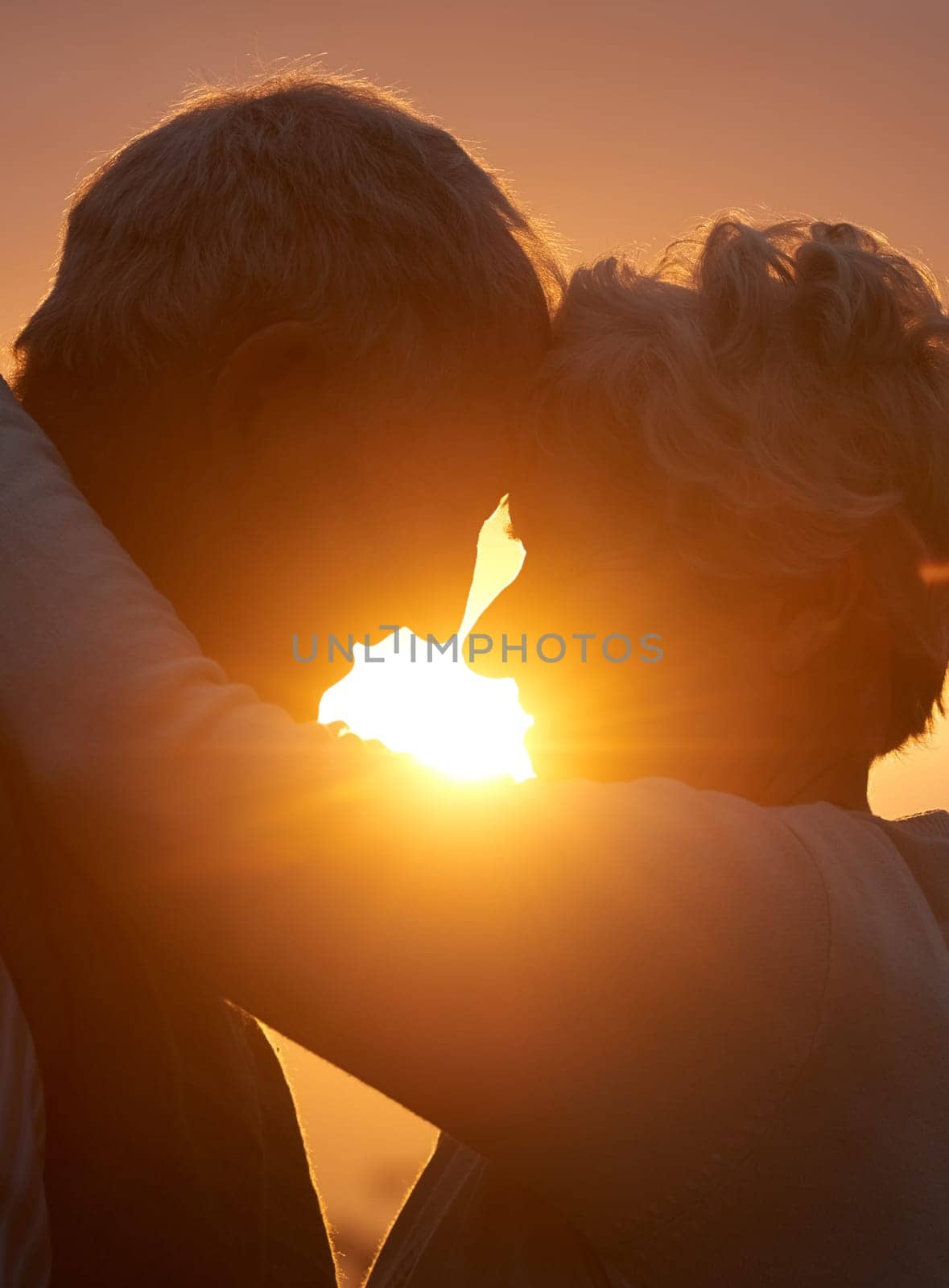 Sunset, senior couple and embrace outdoor, care and bonding for connection together in nature. Man, woman and touch forehead for love, romance and hug for commitment to relationship in retirement.