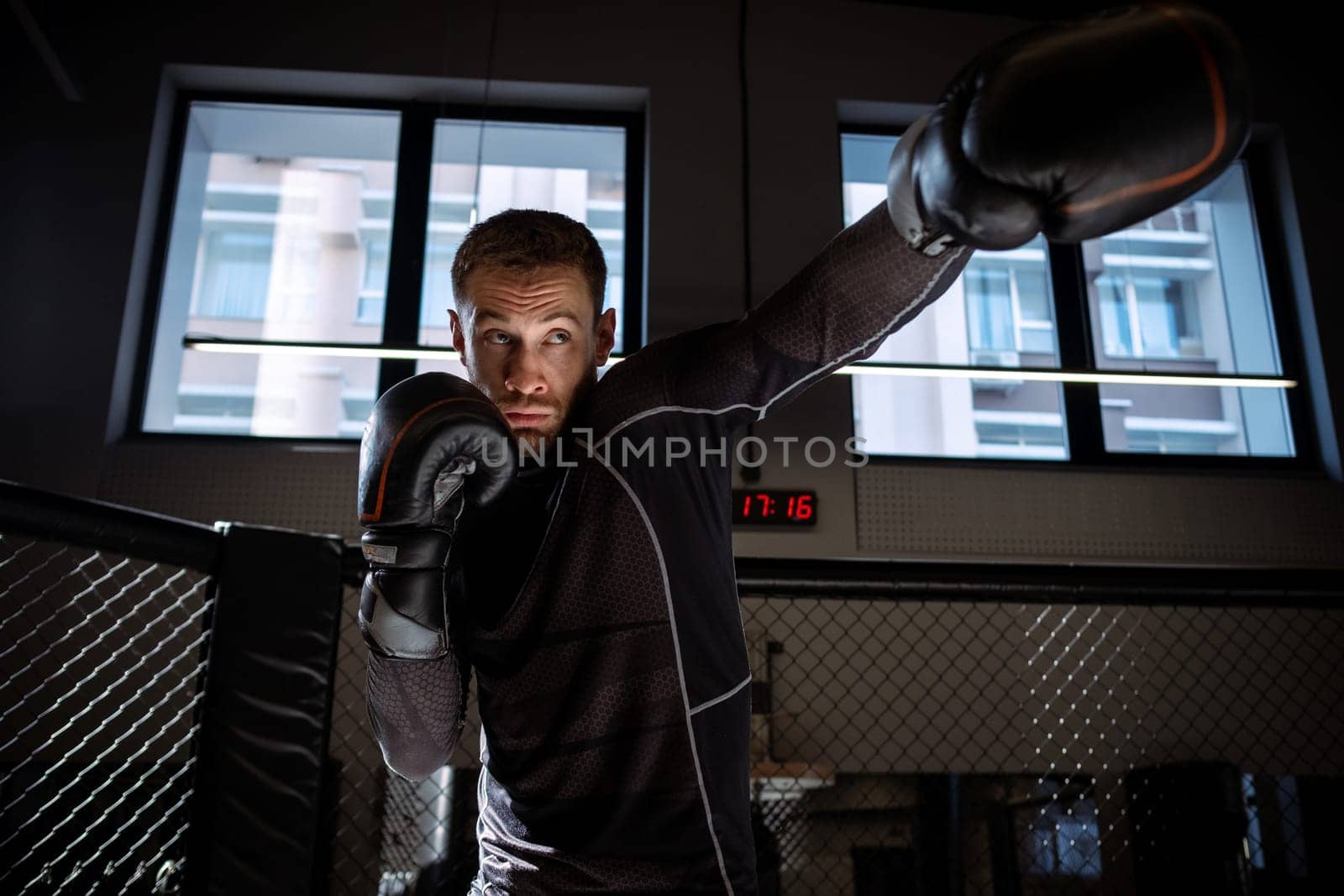 Concentrated young adult bearded boxer honing punching skills while shadowboxing to build speed and muscle memory of body in modern boxing gym