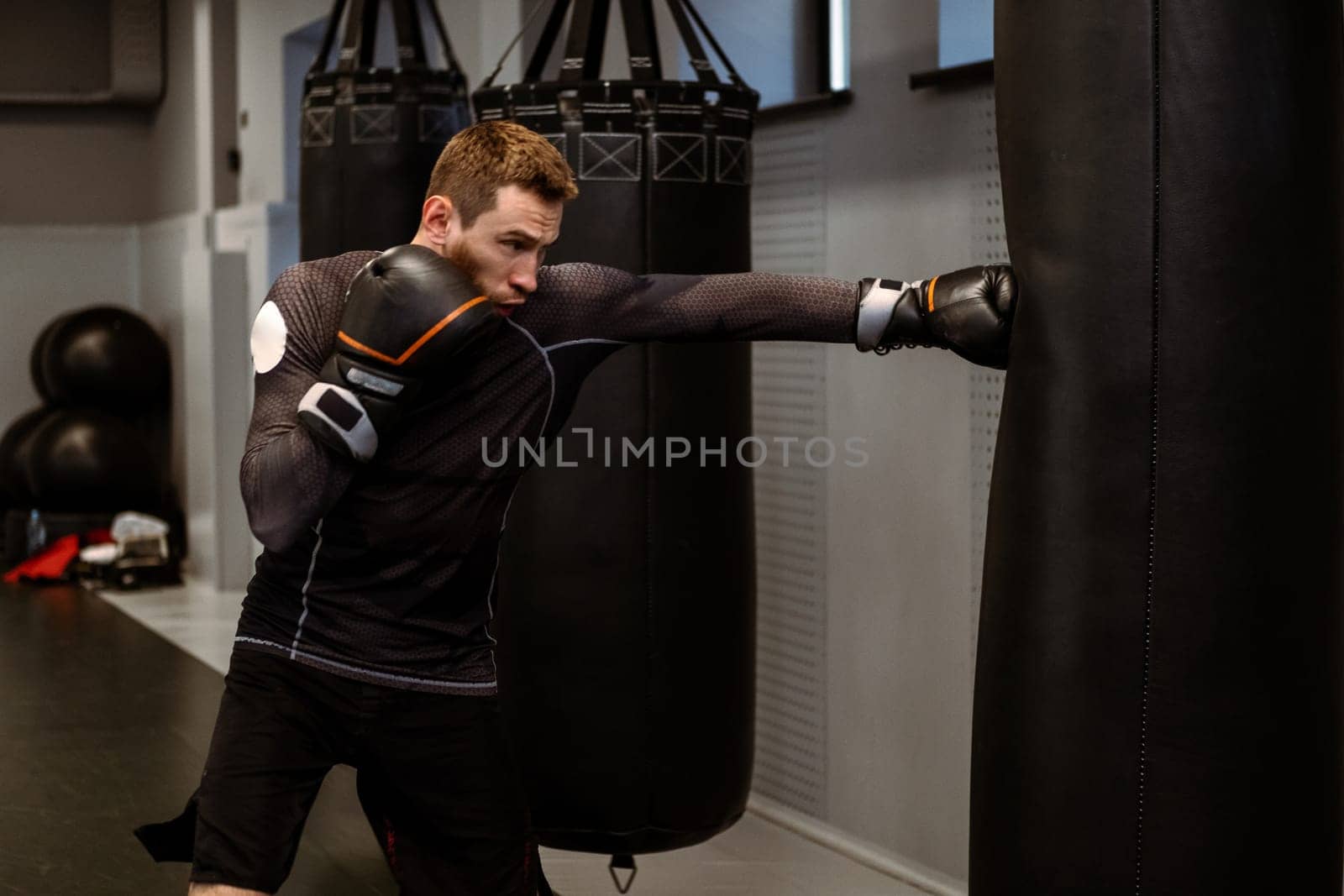 Boxer practicing on heavy bag while training in modern gym by nazarovsergey