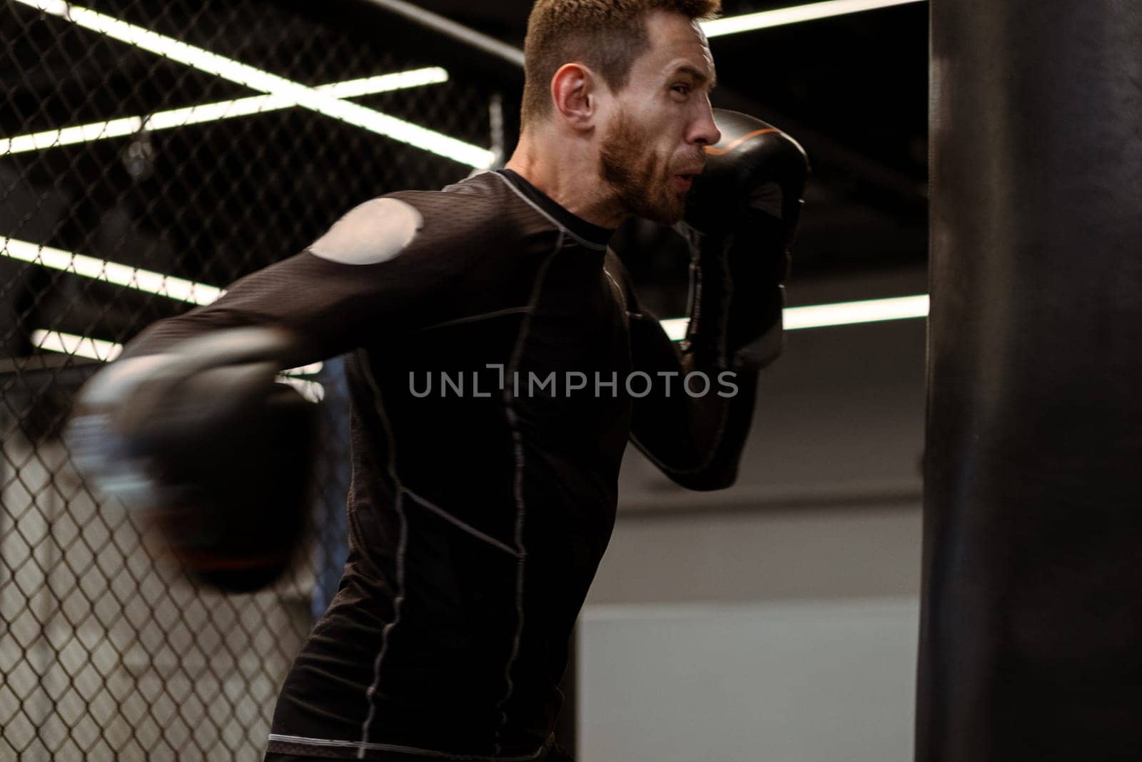 Determined young adult athlete throwing powerful right hook at heavy bag, showcasing power and form in dynamic workout at boxing gym