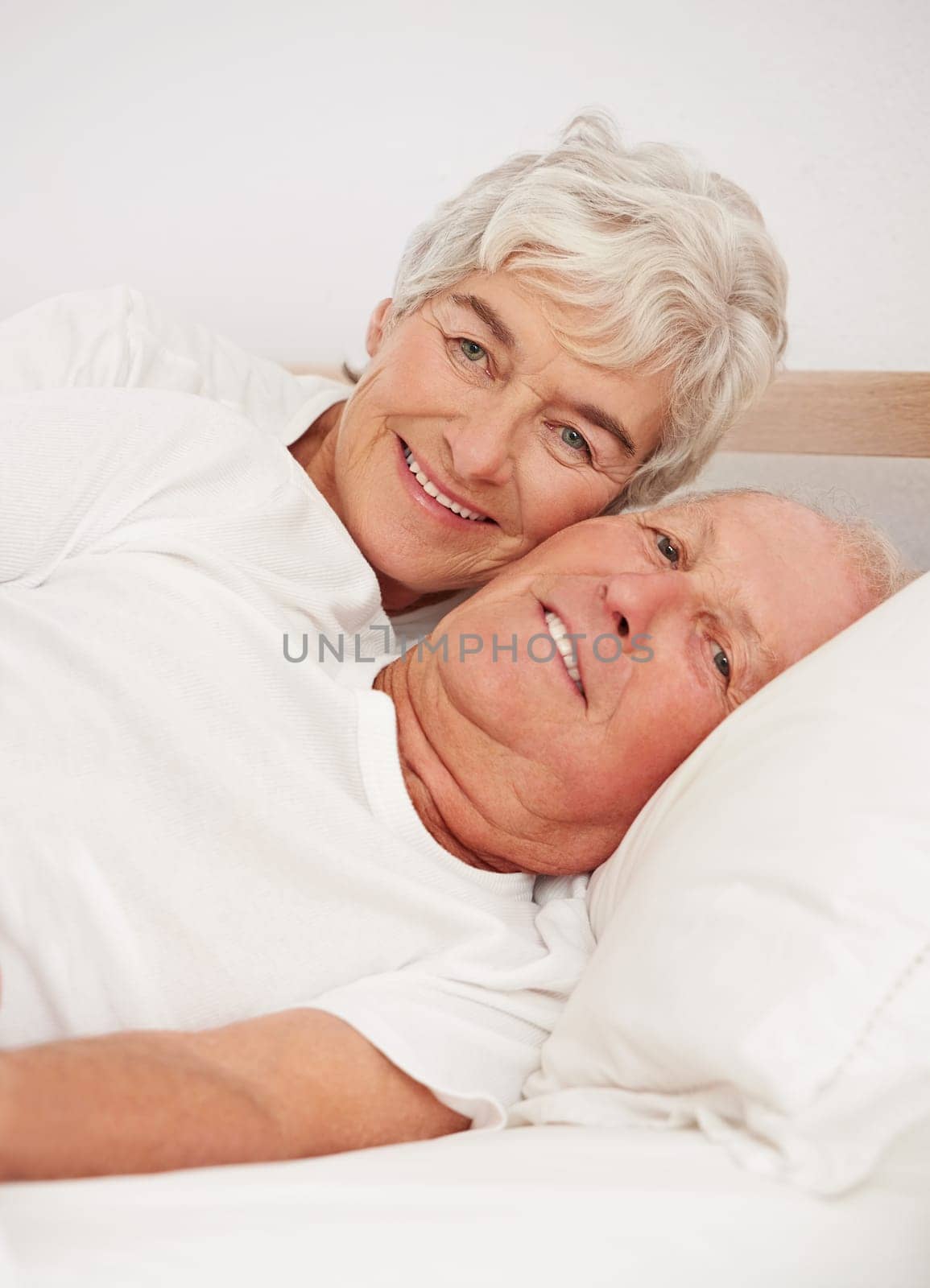 Senior couple, portrait and together in bed, relaxing and love in retirement for bonding on weekend. Elderly people, bedroom and resting or happy in marriage, romance and morning routine at home.