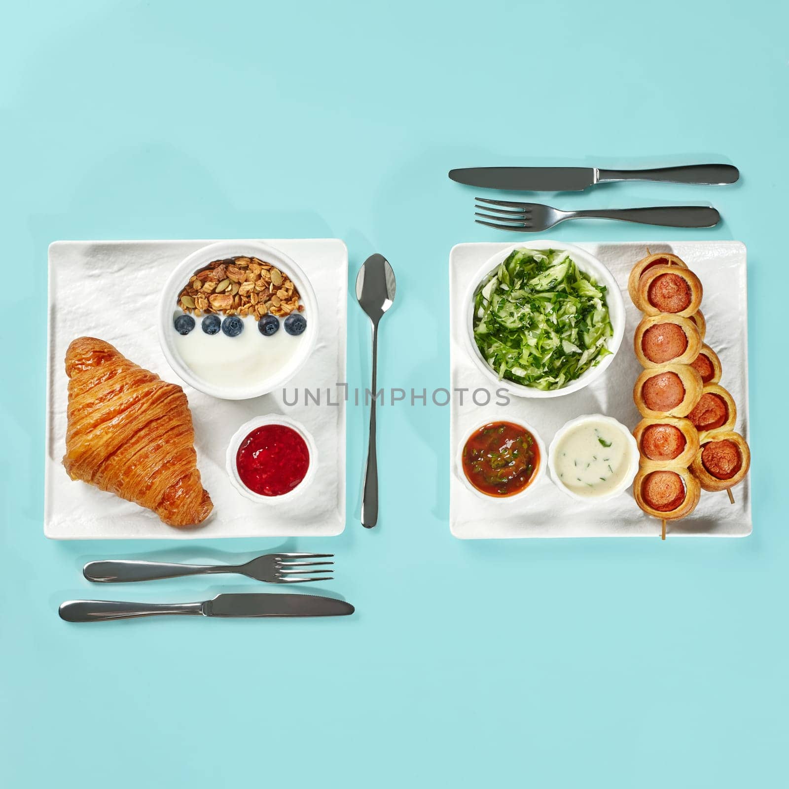 Two breakfast choices presented side by side: continental set with croissant, yogurt, granola and jam, and American set with pigs in blanket salad and dips on white trays on blue background