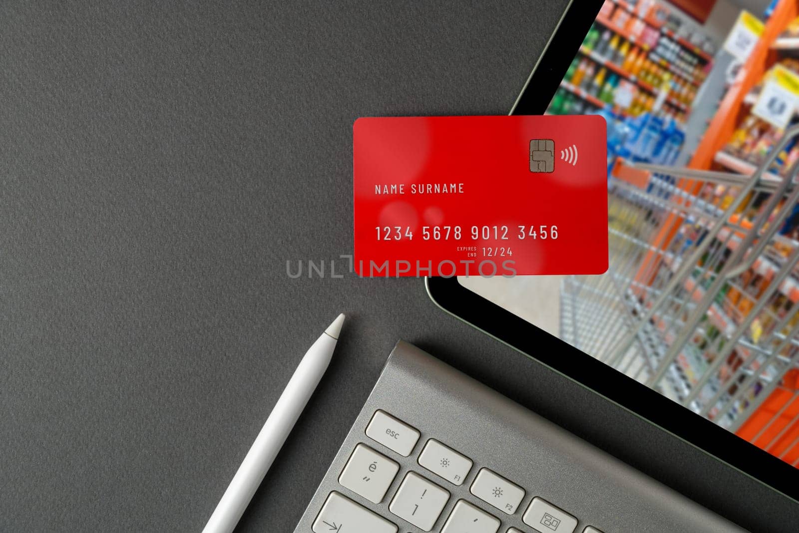 The credit card lies on the tablet and there is a blurry image of the supermarket on the tablet screen