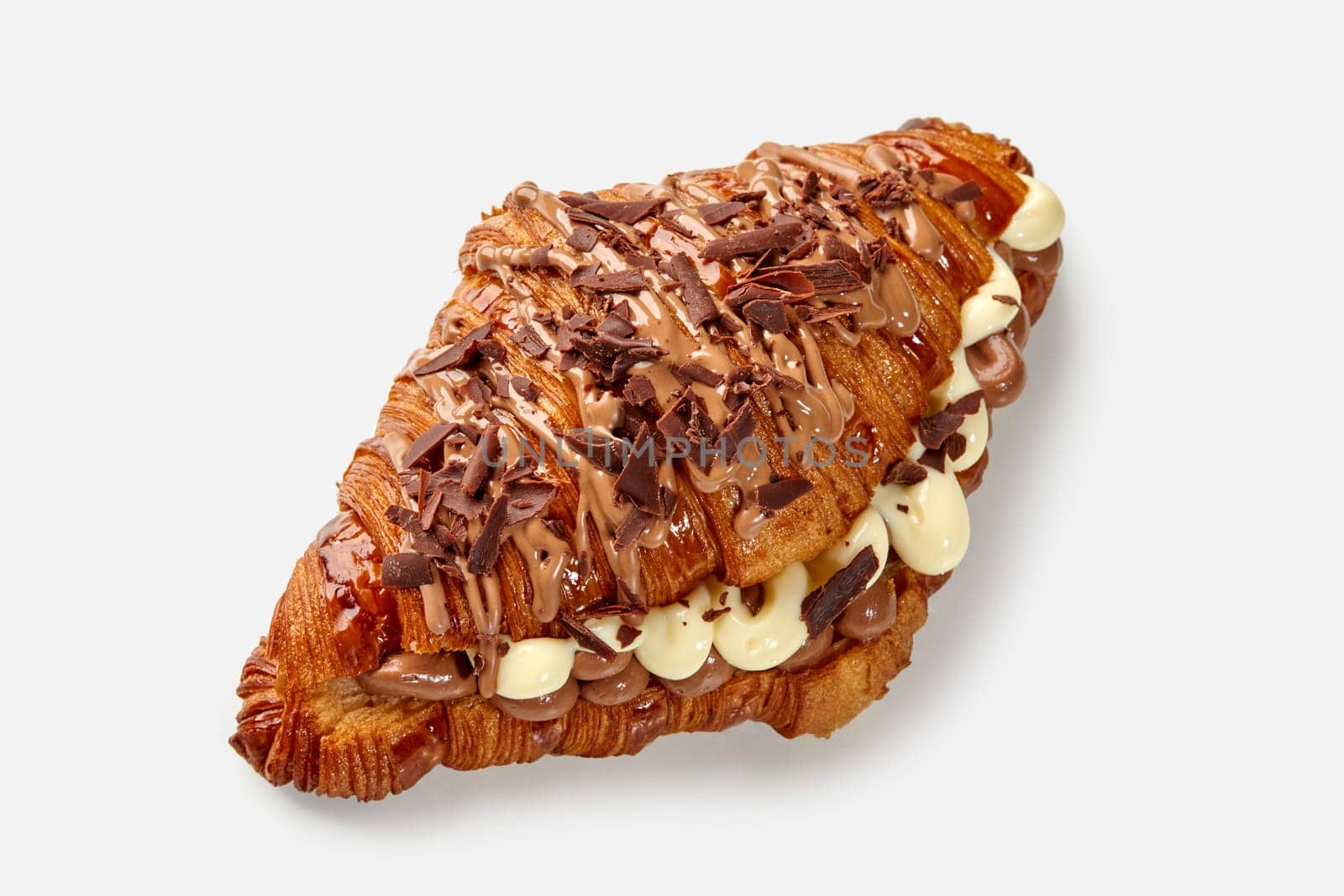 Closeup of gourmet fluffy croissant sandwich with rich creamy filling and chocolate shavings on white background. Delicious French style pastries