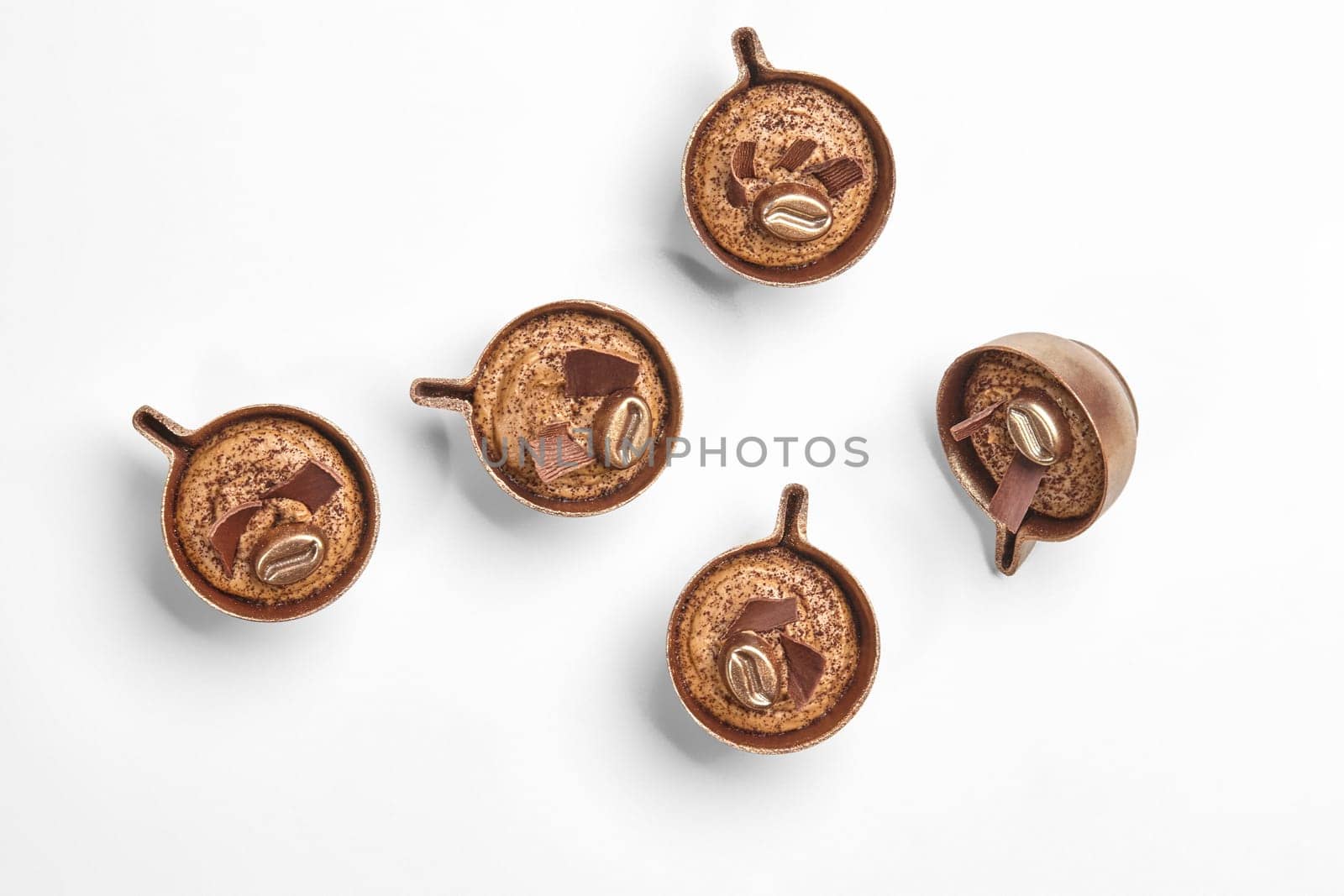 Elegant chocolate candies with coffee filling, crafted to resemble miniature coffee cups, on white background