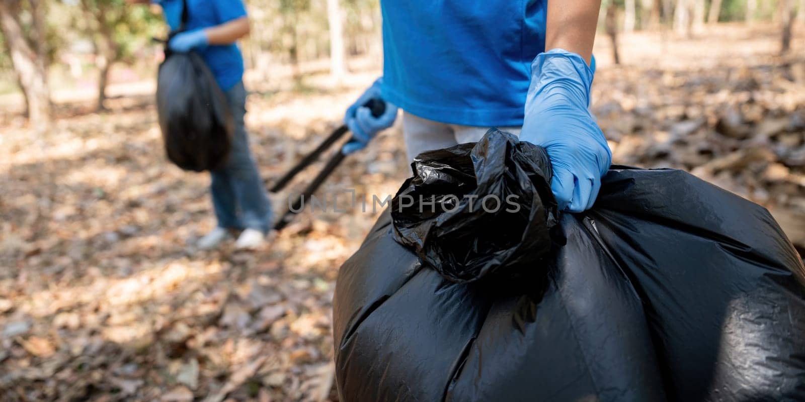 Young people friend volunteer collecting garbage plastic bottles to trash bags. environmental care ecology concept.