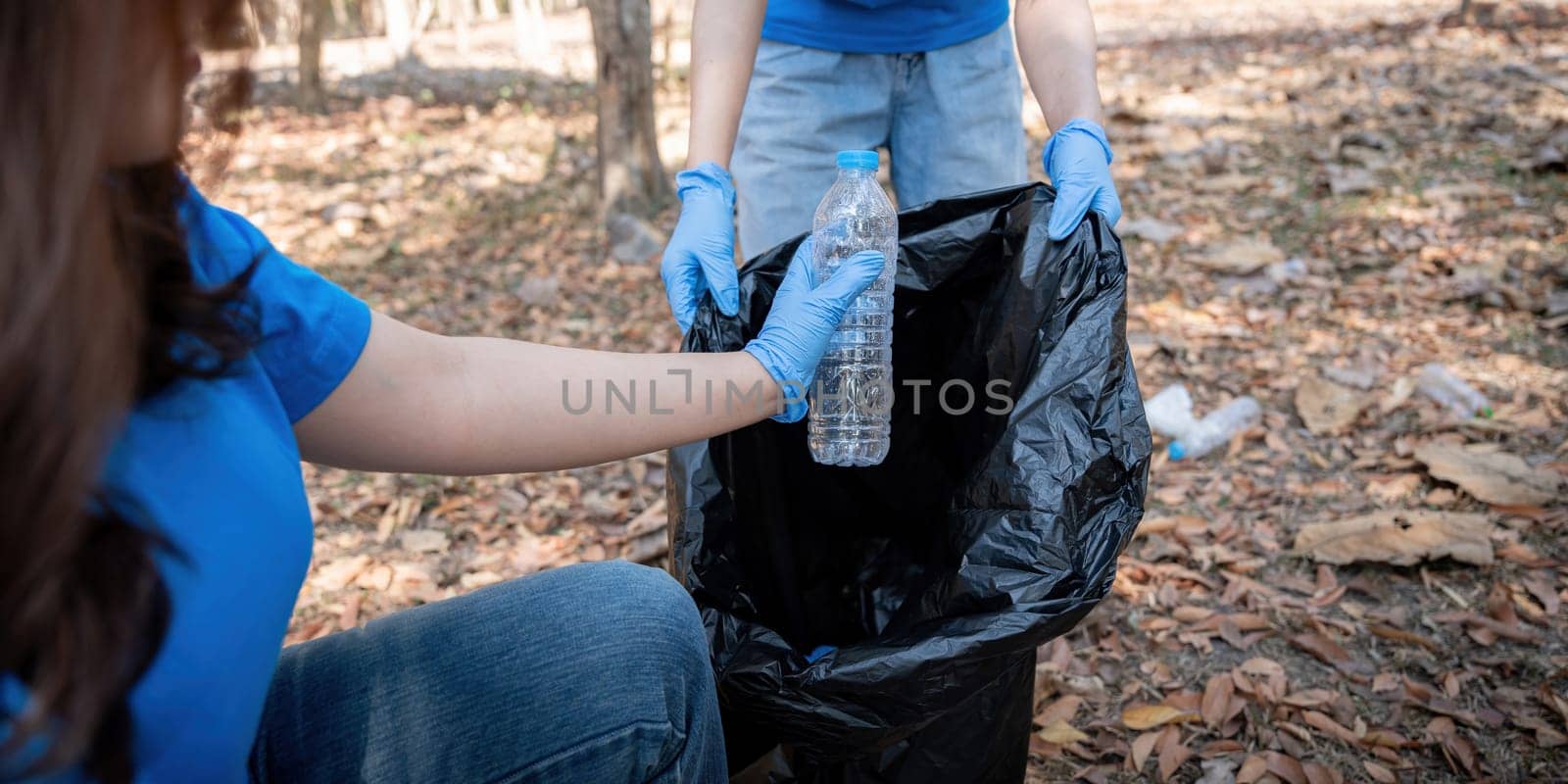 Young people friend volunteer collecting garbage plastic bottles to trash bags. environmental care ecology concept by nateemee
