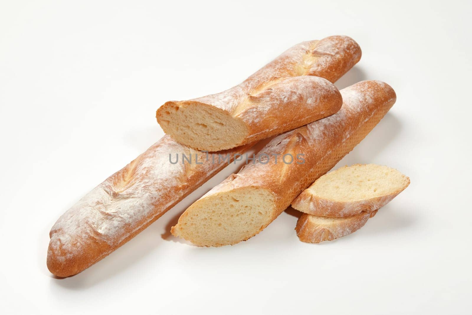Closeup of freshly baked whole and sliced wheat baguettes isolated on white background. Main staple. Artisanal breadmaking concept by nazarovsergey