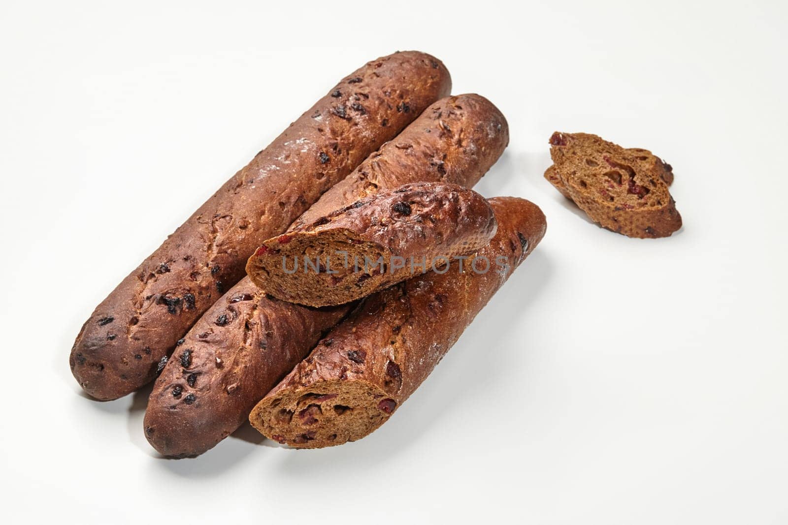 Dark rye baguette loaves with tart cranberries, featured in detailed close-up on white background. Artisan bakery products concept