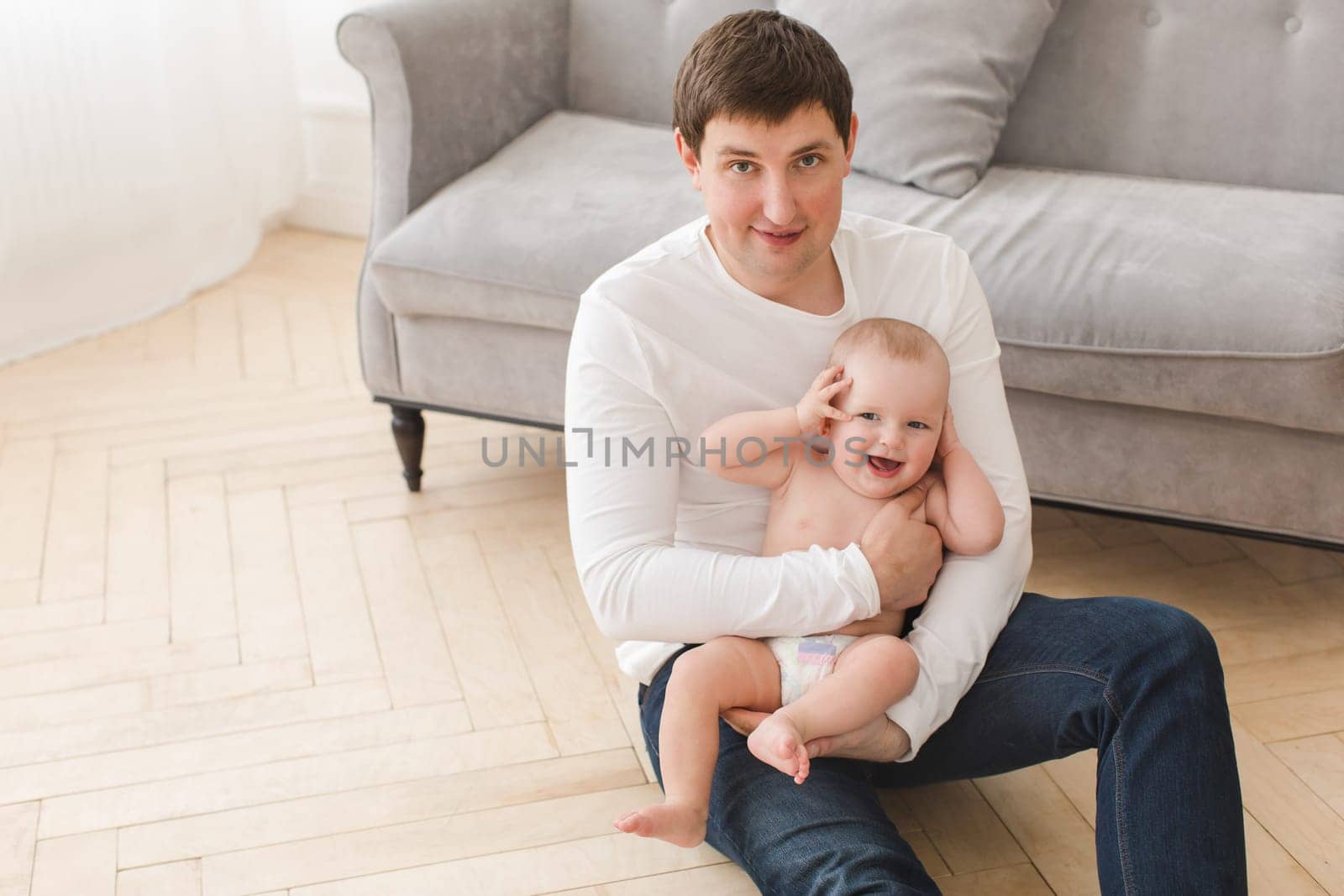 Happy father with cheerful infant on hands by Demkat