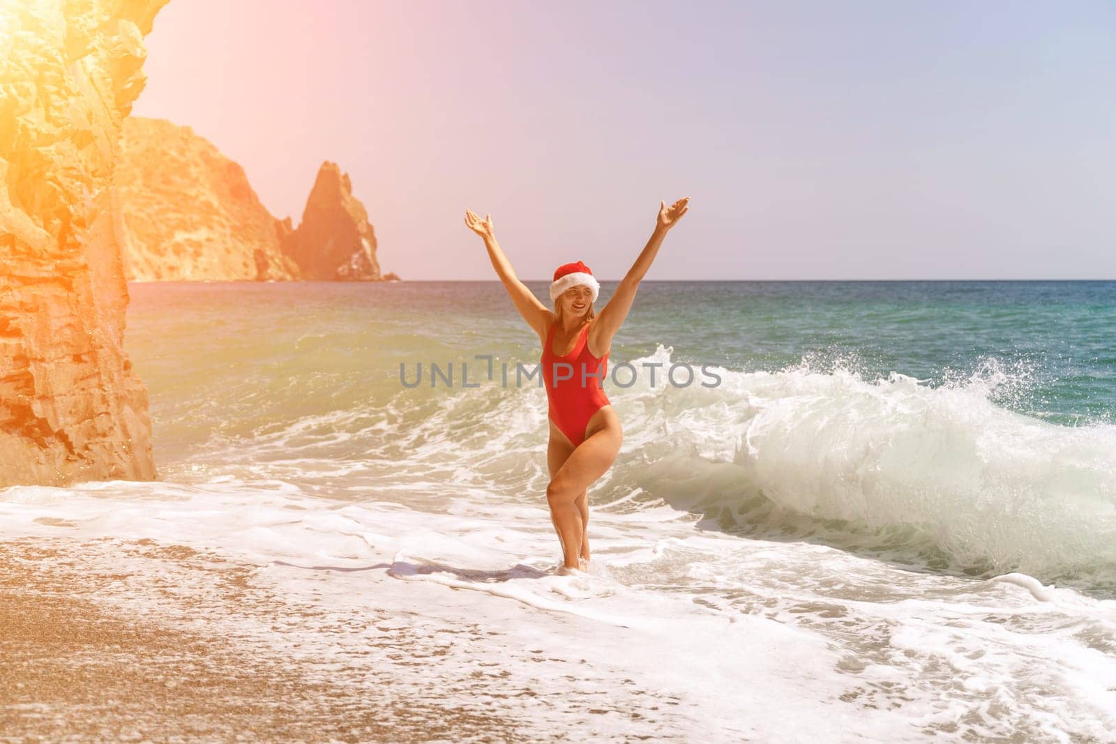A woman in Santa hat on the seashore, dressed in a red swimsuit. New Year's celebration in a hot country