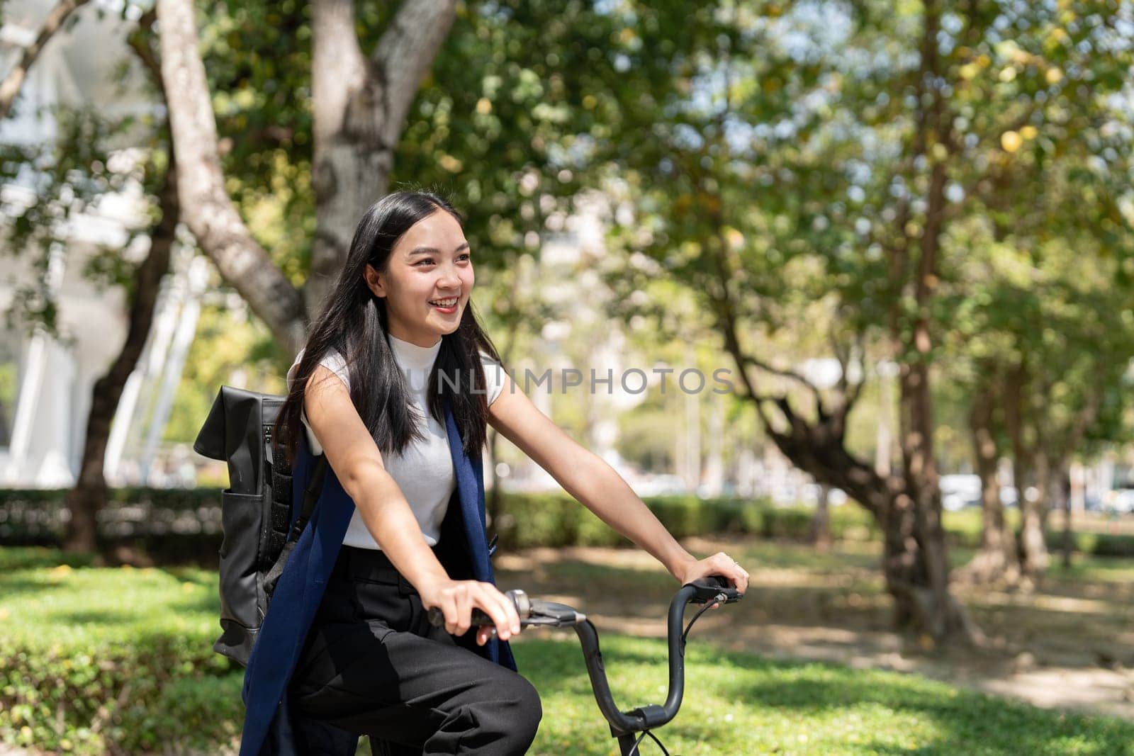 Asian businesswoman in bicycle go to work at office. Bike commuting, happy businesswoman using eco transport, Concept of eco lifestyle.