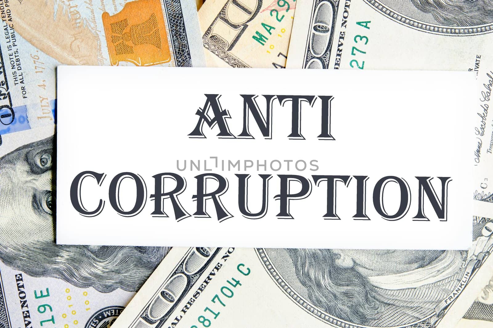 ANTI CORRUPTION text writing on a white card against the background of banknotes