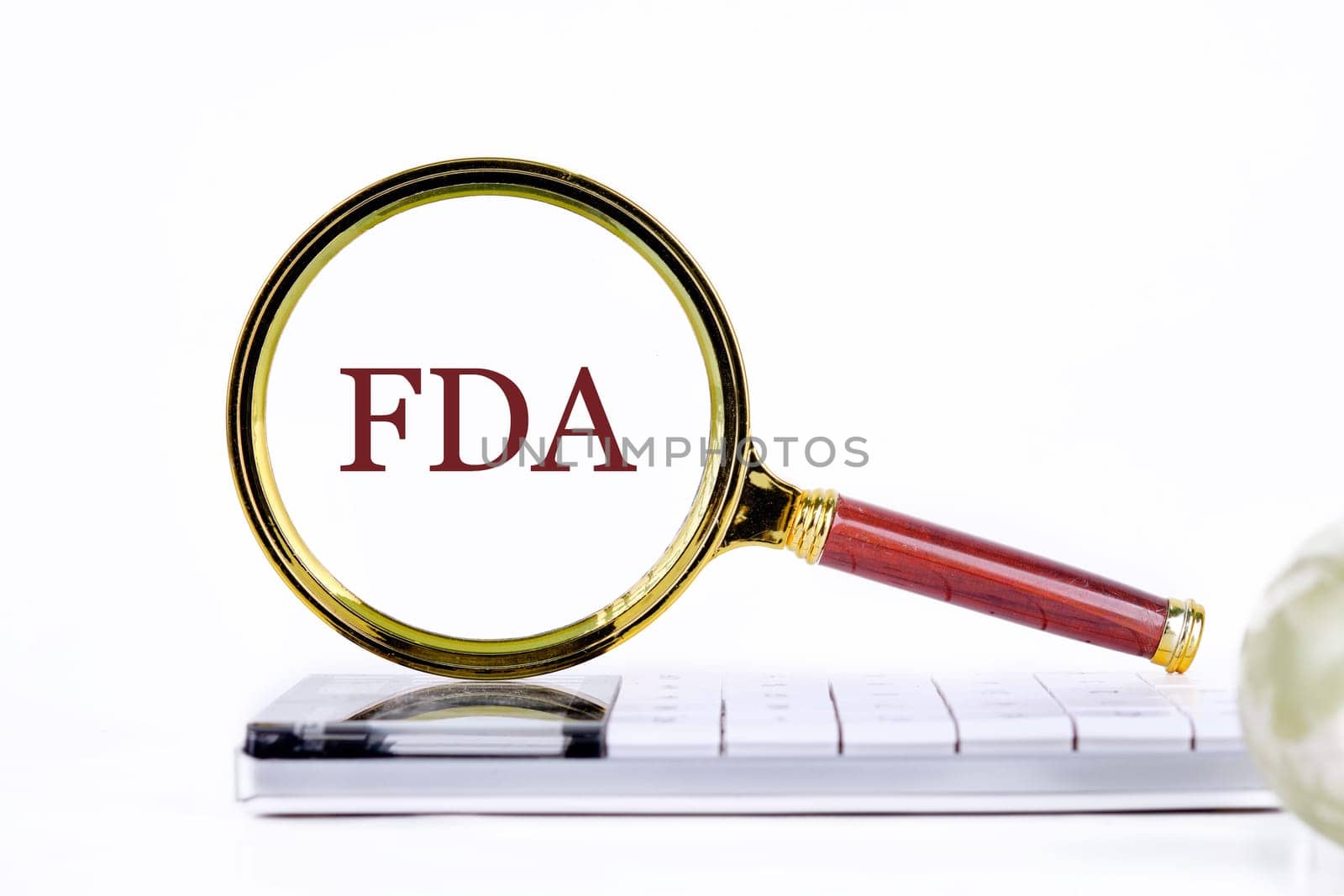 Word FDA written through a magnifying glass on a calculator on a light background. Business development concept