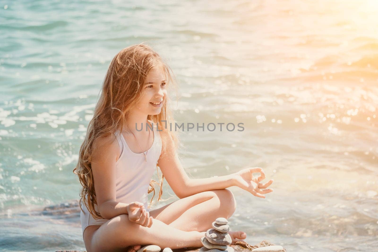 Woman with daughter bilds stones pyramid on seashore on a sunny day on the blue sea background. Happy family holidays. Pebble beach, calm sea. Concept of happy vacation on the sea, meditation, spa by panophotograph