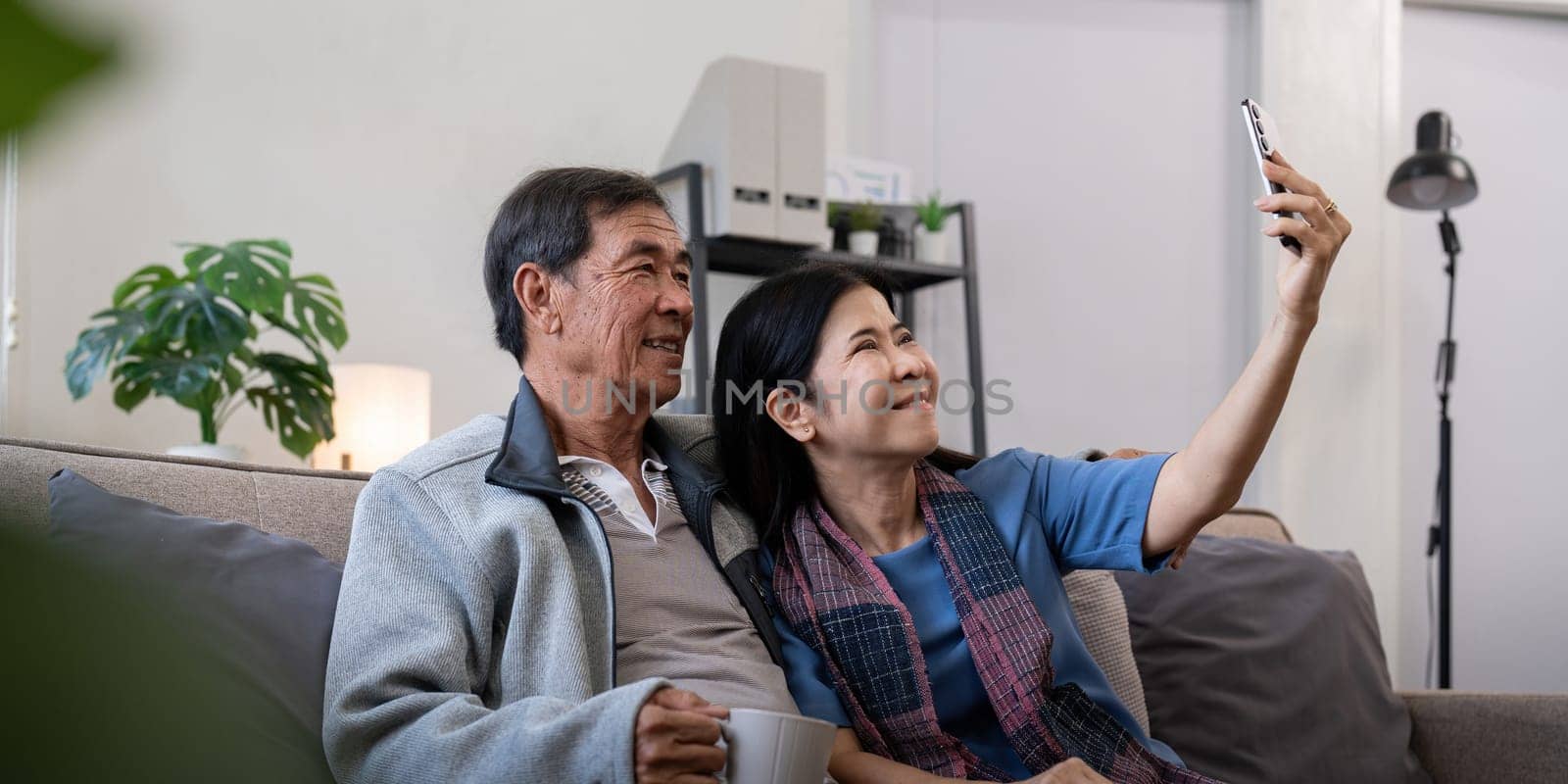 Happy old couple elderly taking selfie on cellphone, senior mature spouses wife and husband laughing holding phone make self portrait on smartphone camera by nateemee